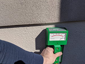 EIFS Inspection moisture scan device held up to the outer wall of a home.